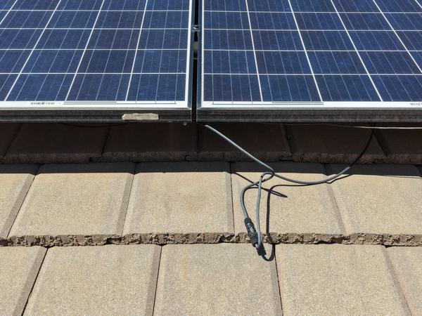 Exposed DC wiring resting on roof tiles